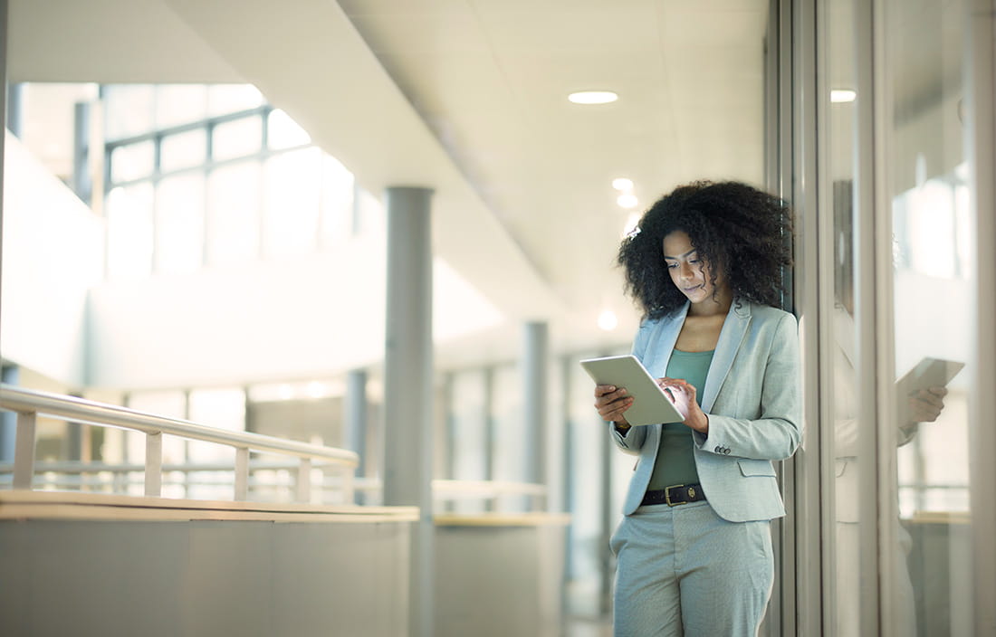 Younger businesswoman using a tablet device in an open foyer area.