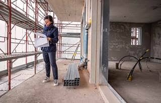 Woman standing at a construction site looking at blueprints