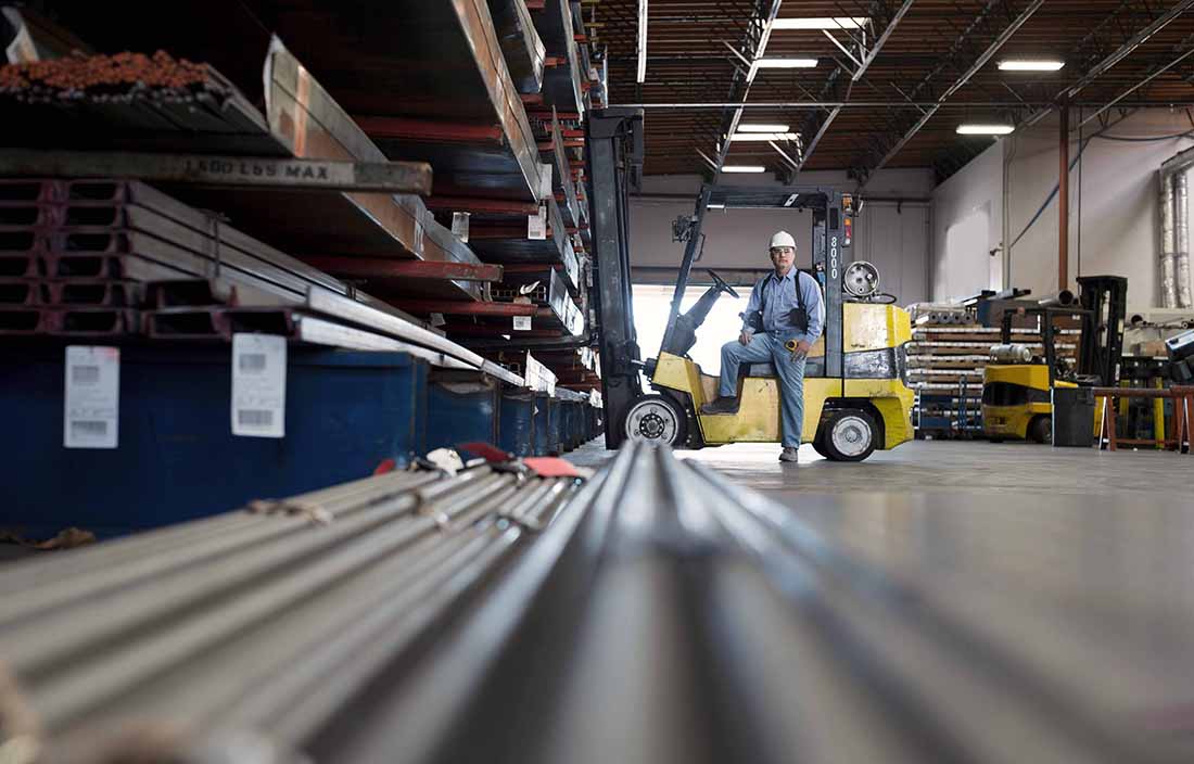 Auto worker driving a fork lift in a warehouse.