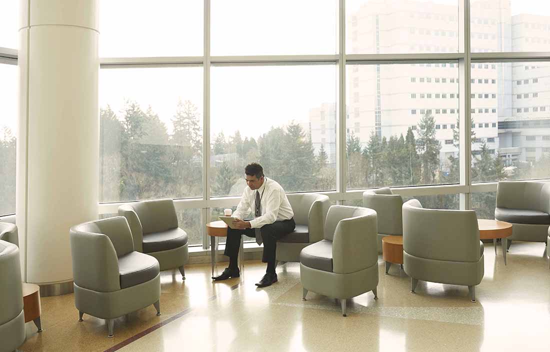 Businessman sitting in lobby area for a building reading news.