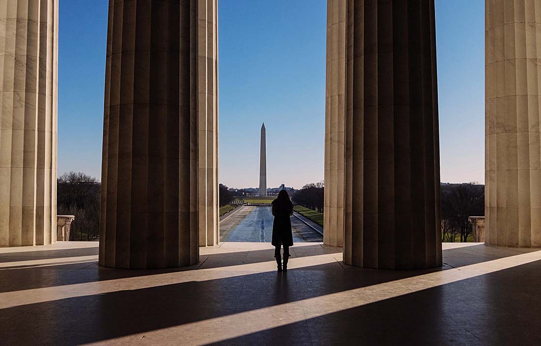 Woman standing by U.S. government building next to big pillars.