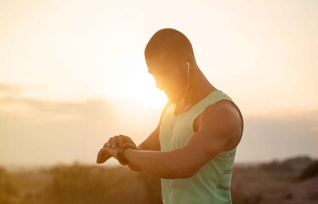 Man in workout gear checking is smart watch fitness device.