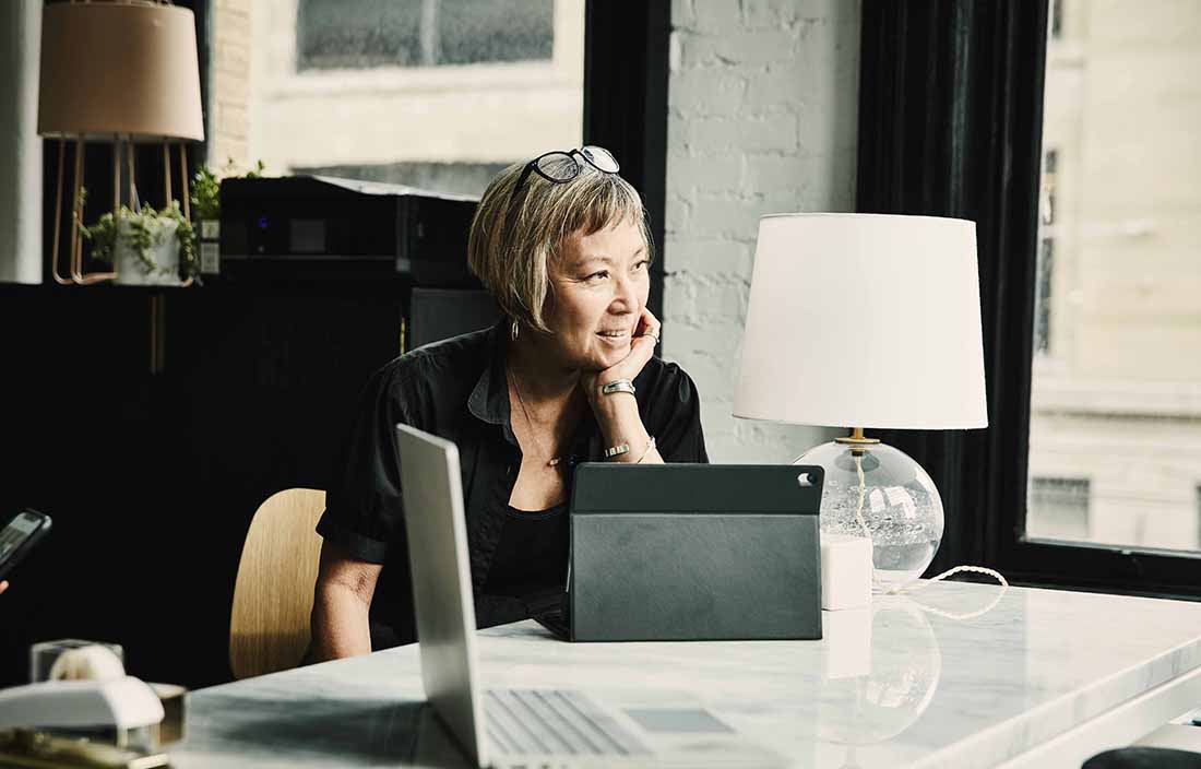 Woman sitting at a table with an open laptop and tablet