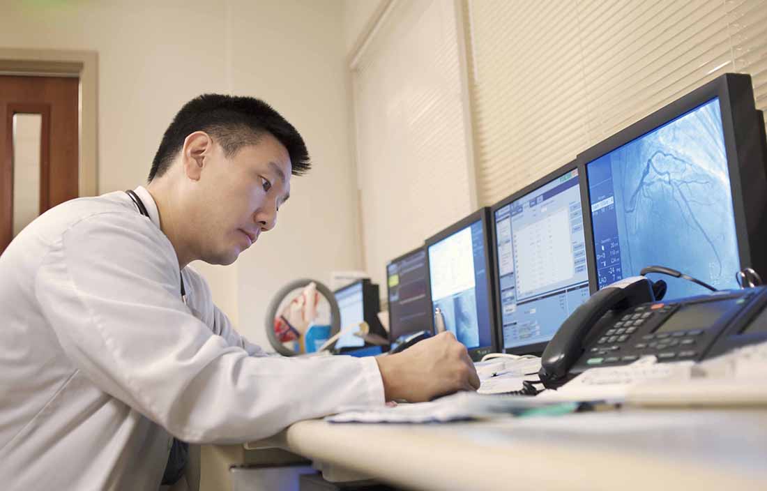 Man working in front of multiple computer screens and a phone