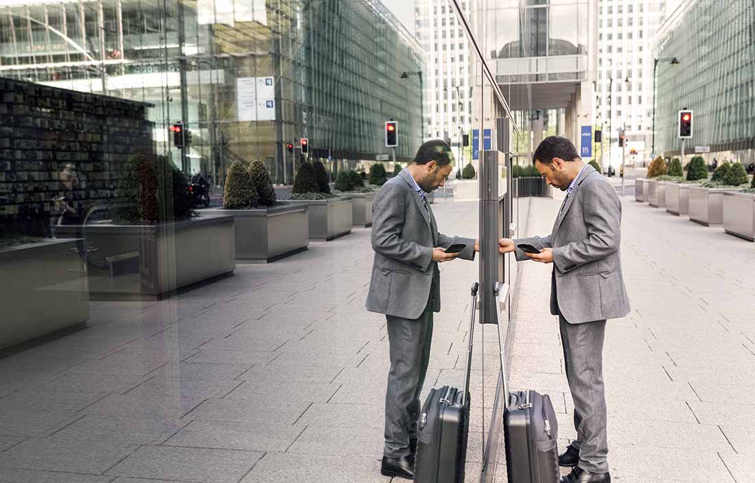 Businessman standing on the street using an ATM machine.