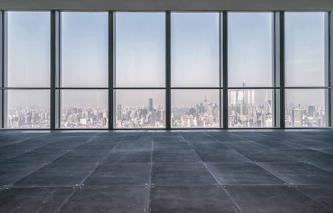 Empty room with floor to ceiling glass windows looking out of a high rise building