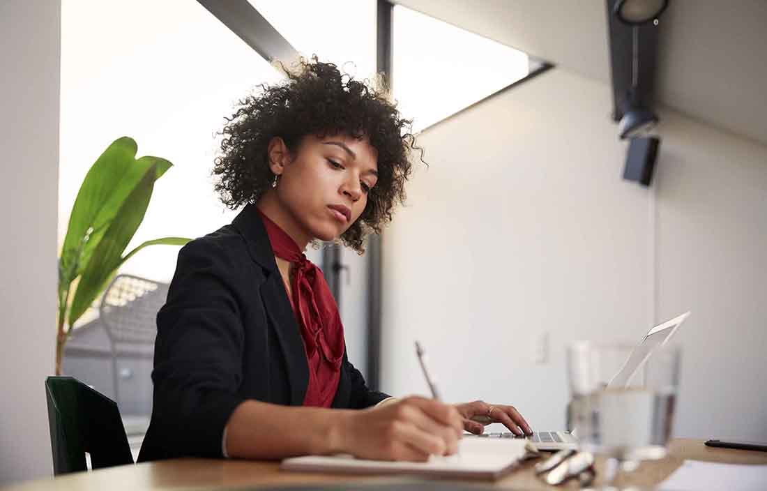 Woman sitting at a table, writing in a notebook