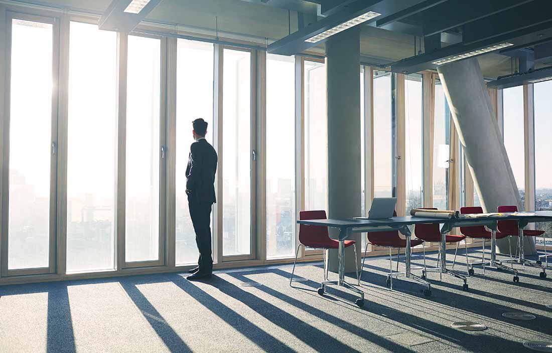 Businessman looking out glass window in a conference room.