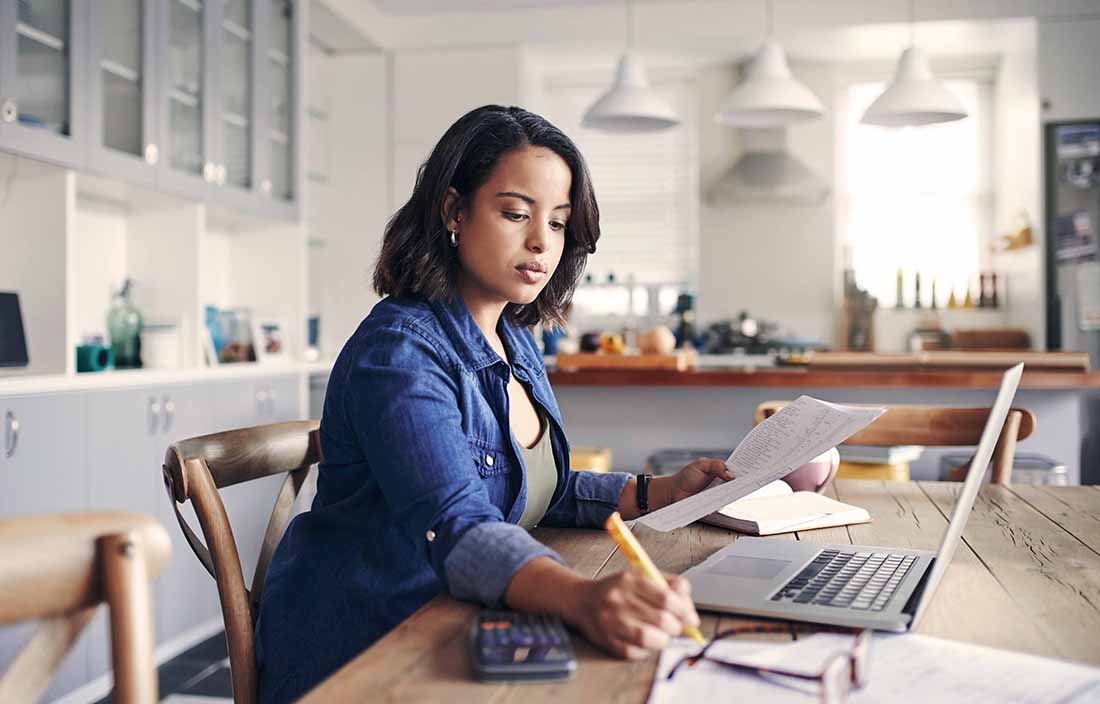 Woman sitting at a kitchen table reading documents