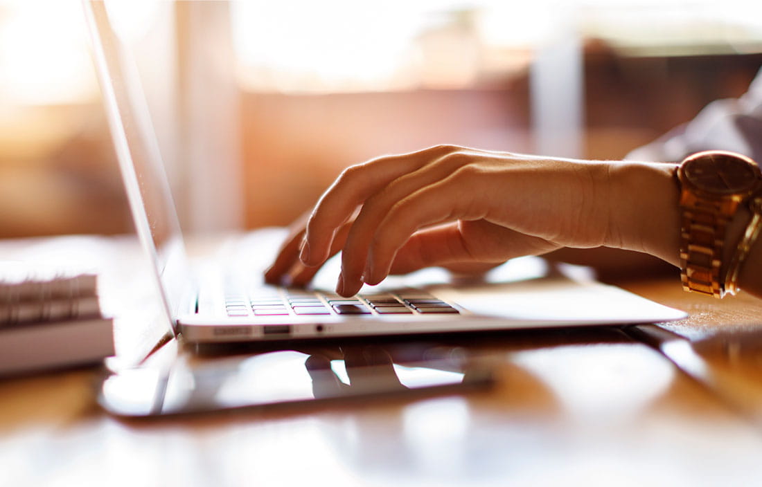 Close-up of hands typing on a laptop.