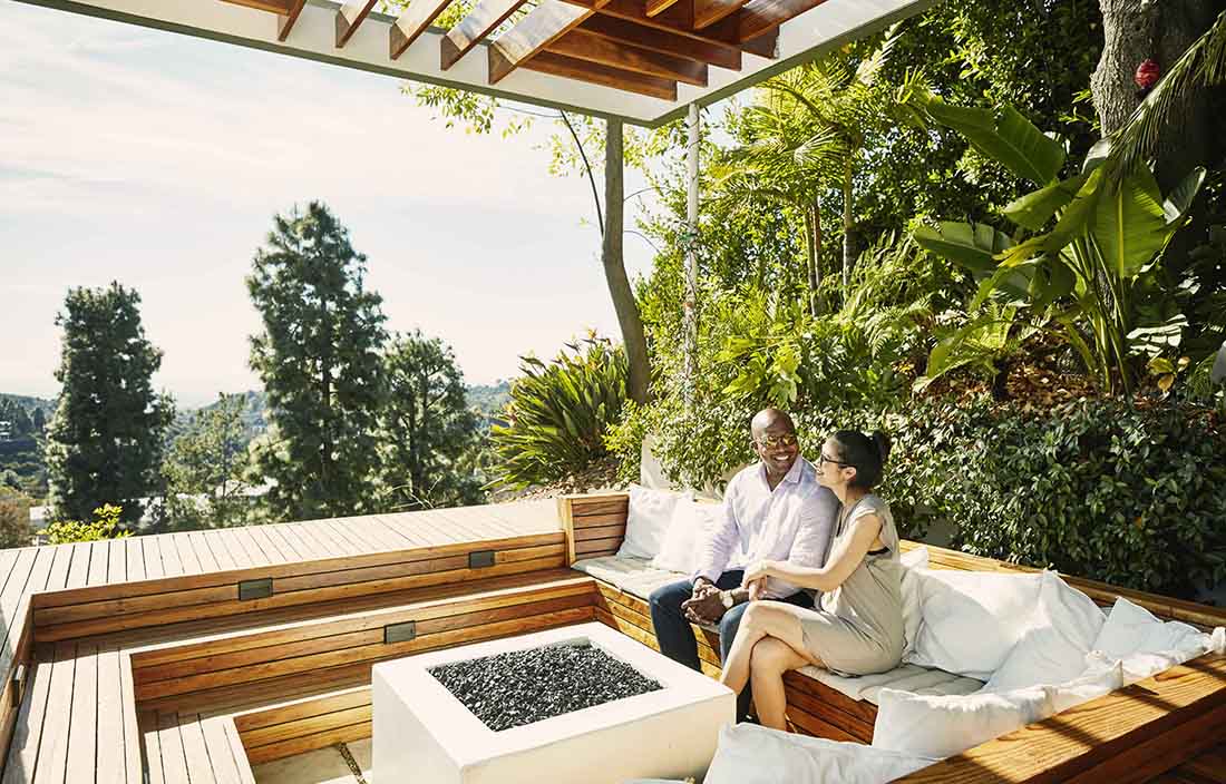 A couple smiling and holding hands in an outdoor area. 