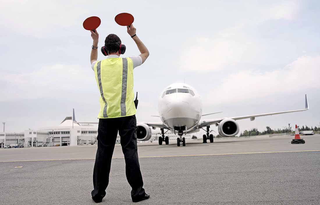 Runway worker at an airport guiding a plan for landing.