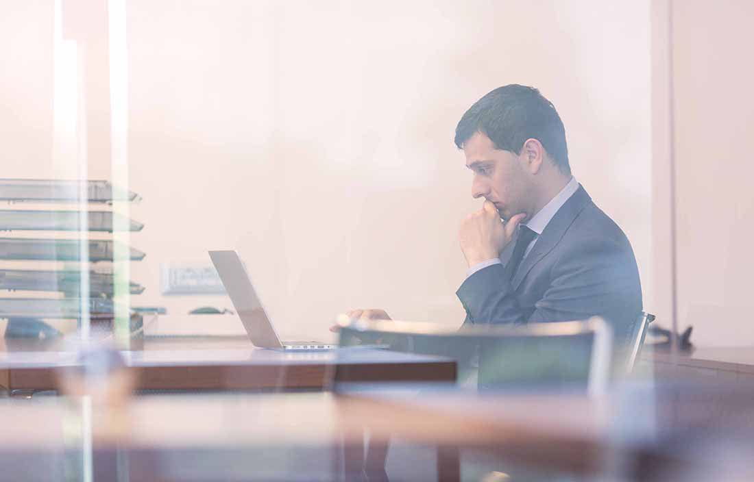 Businessman looking at his laptop computer while working at his desk.