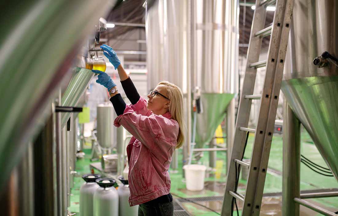 A woman working in a factory nearby metal silos.