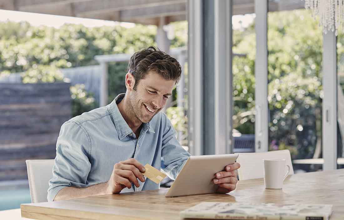 Man smiling while using a handheld tablet in an outdoor area.