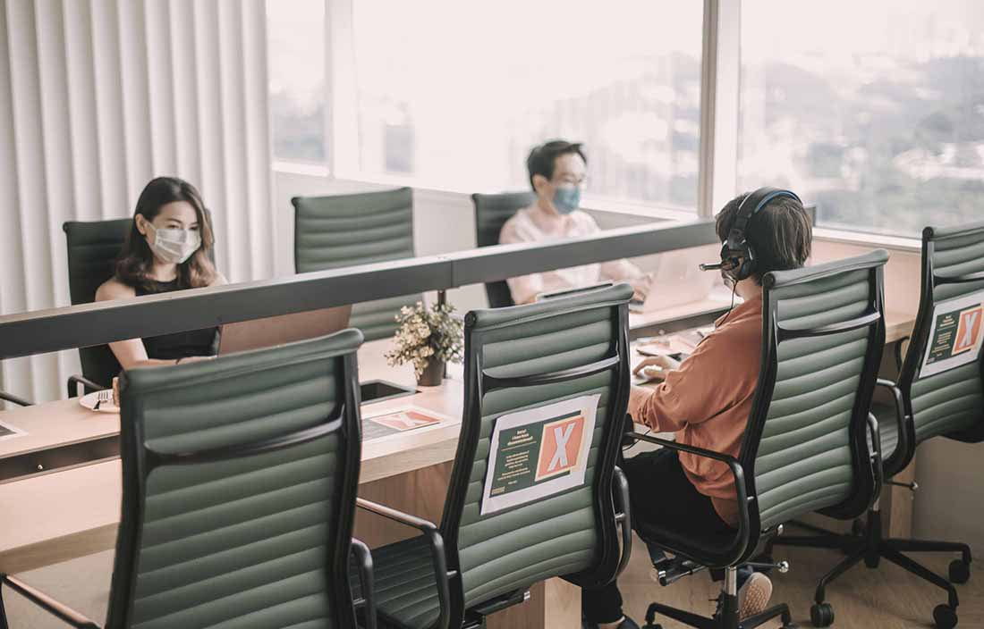 Business people in a conference room wearing protective face masks while working.