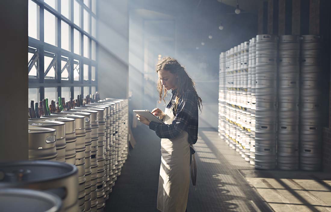 Brewery worker using a handheld tablet device in a brewery.