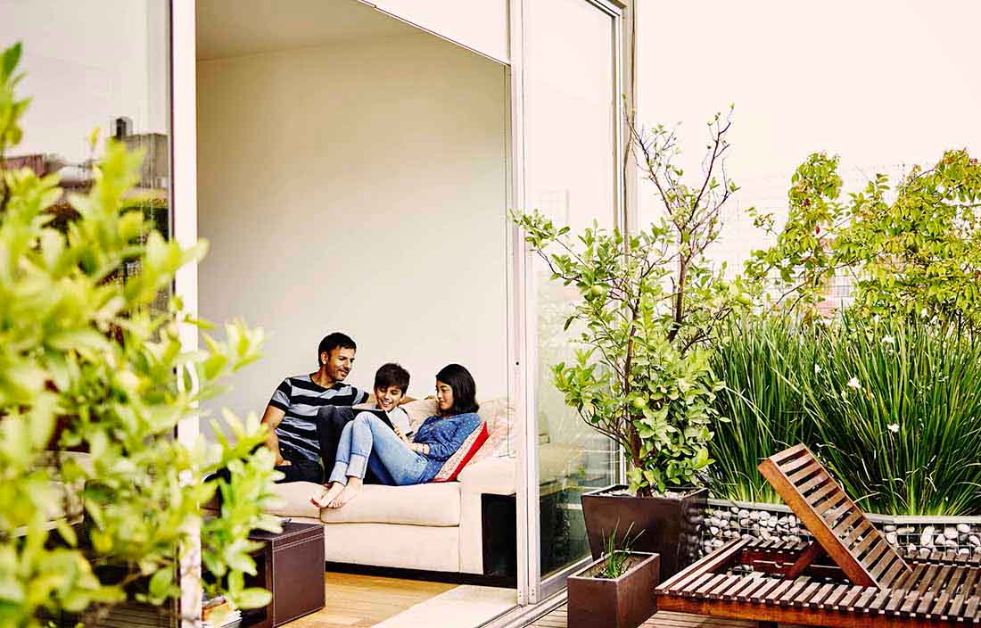 A family sitting in a living room together looking at a handheld tablet device.