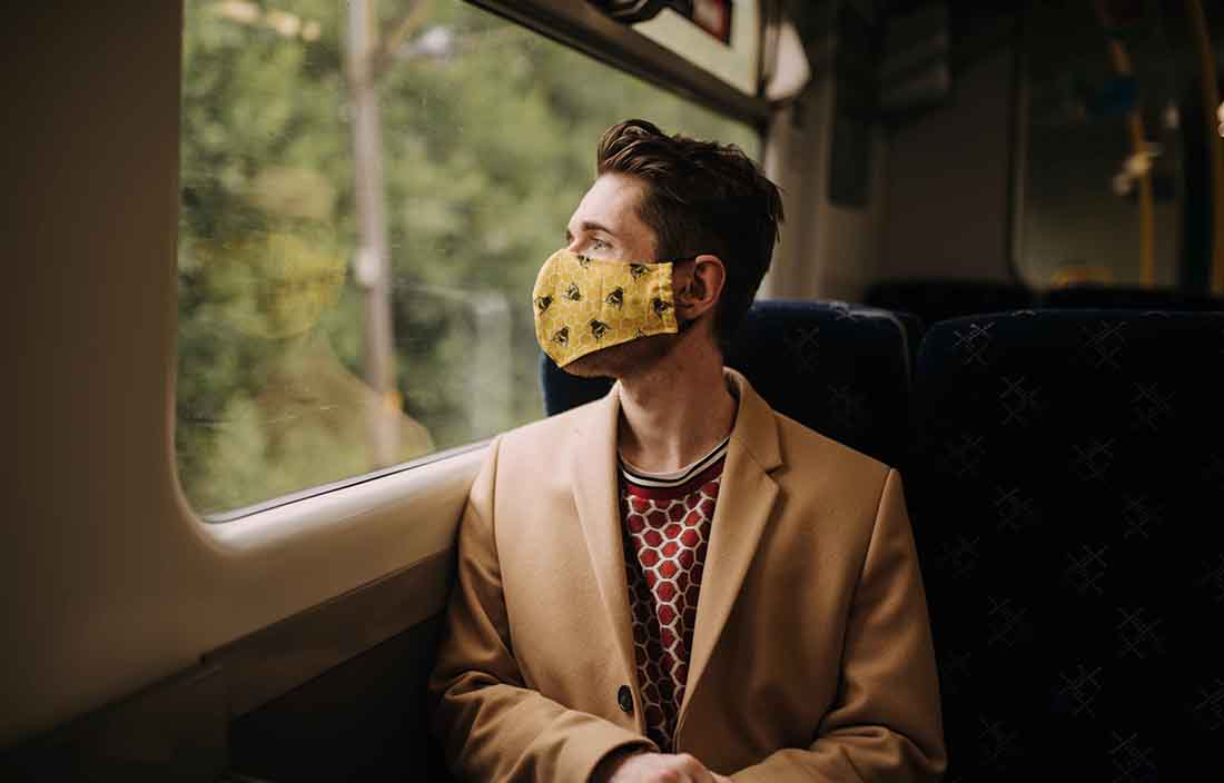 Man sitting on a train wearing a mask