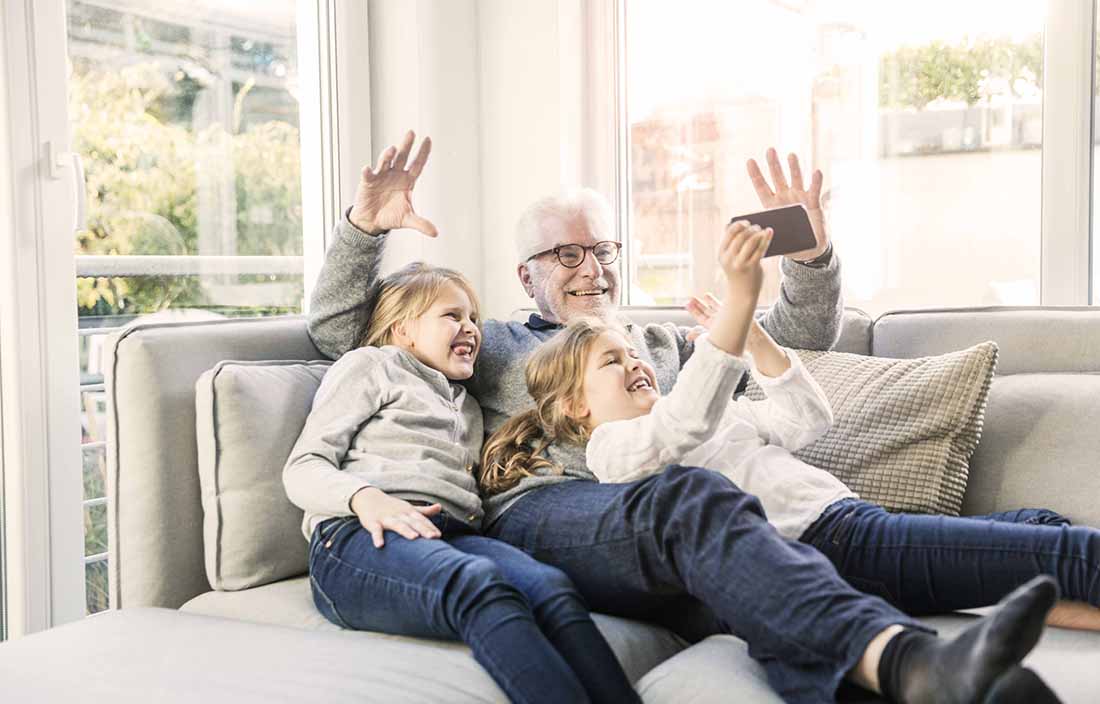 Elderly man hanging out with grand children in a family living room.