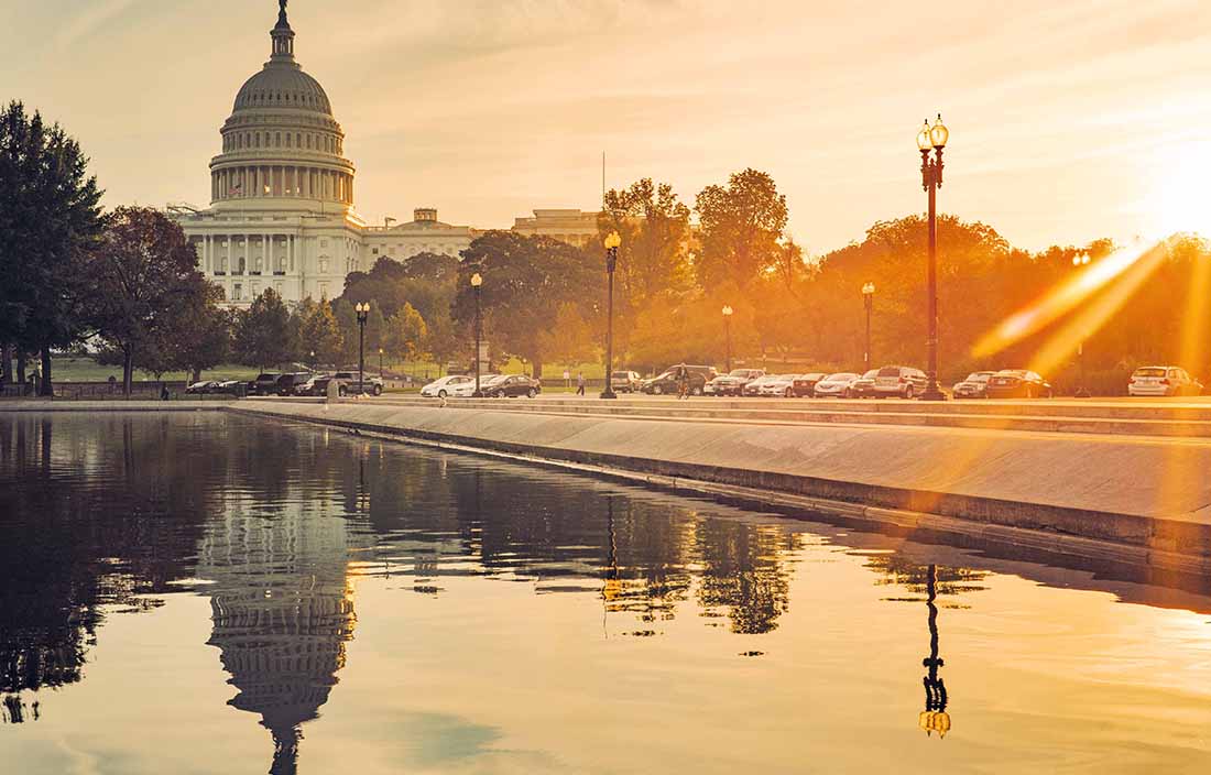 View of the United States Capitol building at dawn with the sun setting.