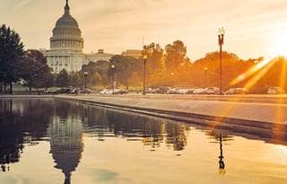 View of the United States Capitol building at dawn with the sun setting.