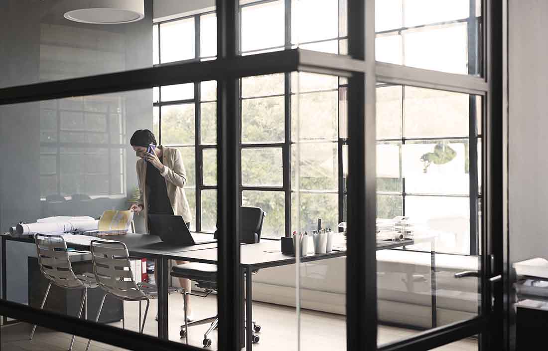 Businessperson in an office standing while taking a call on a cell phone.