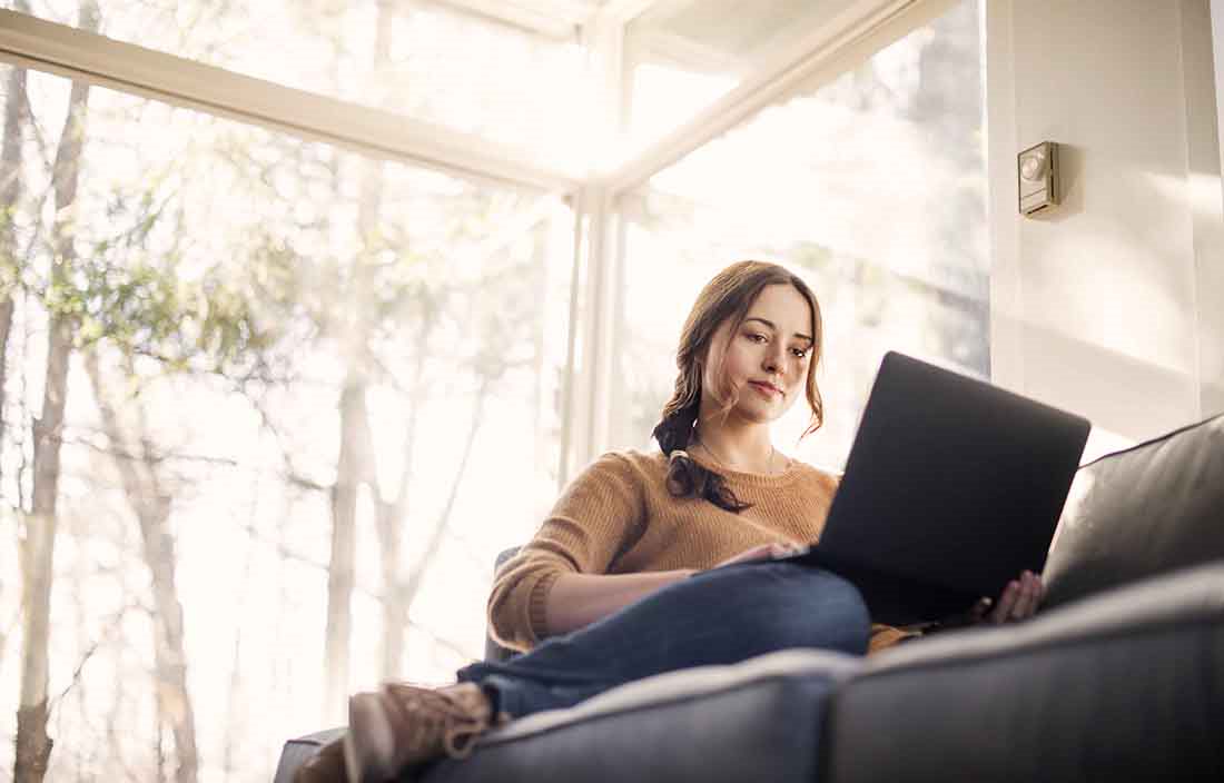 Businessperson in casual clothes using a laptop while sitting on a couch.