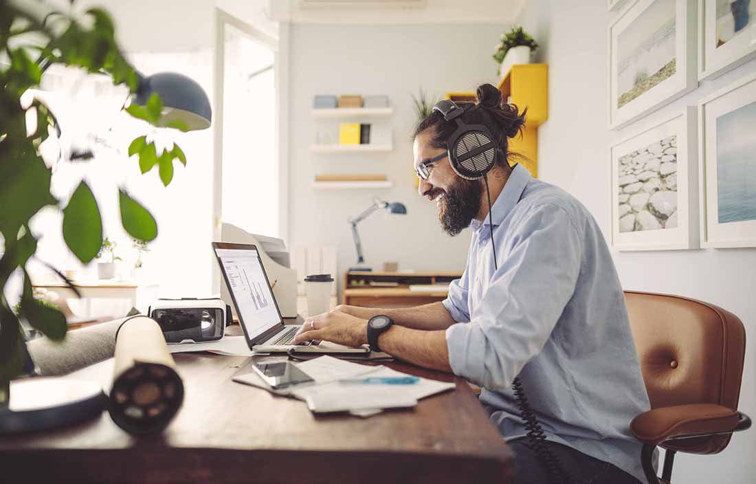 Man wearing headphones using a laptop computer.