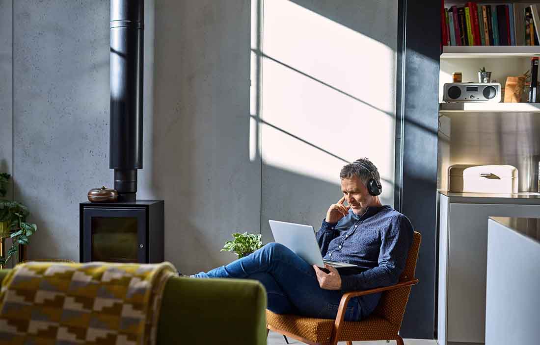 Businessman in casual clothes wearing headphones using laptop computer.