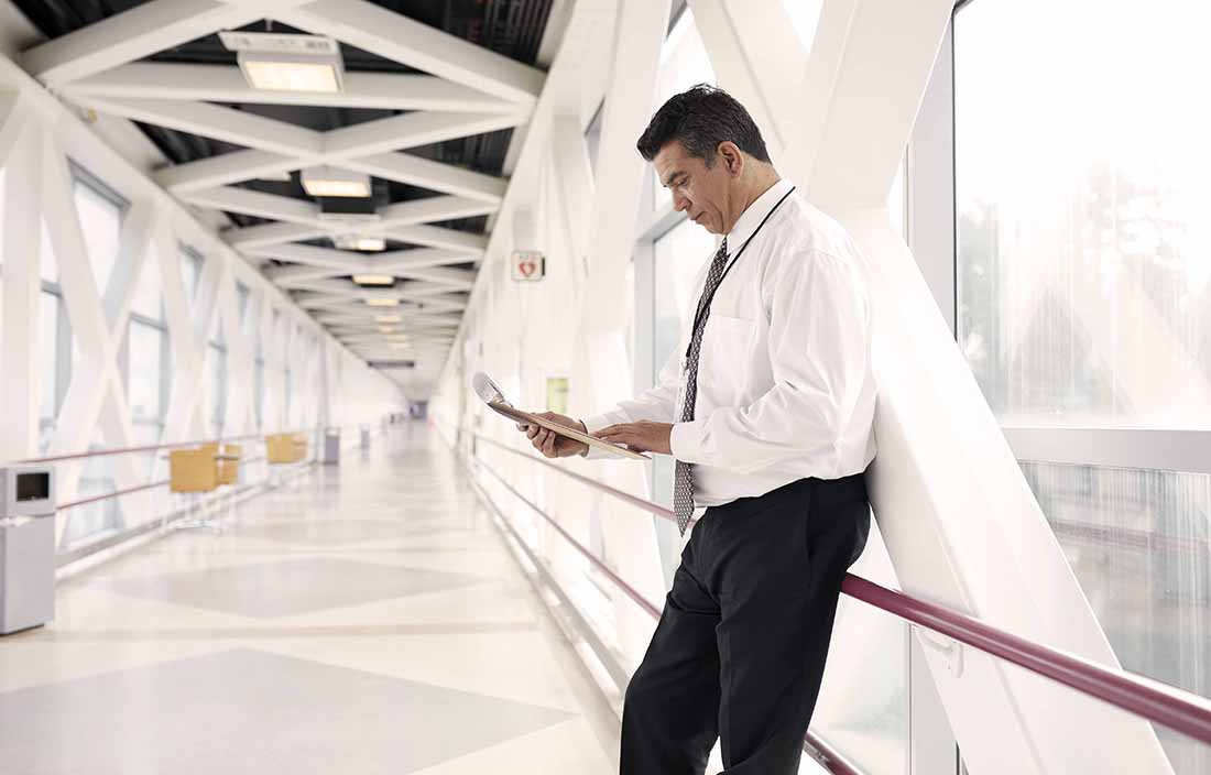 Business professional leaning on a railing in a hallway.