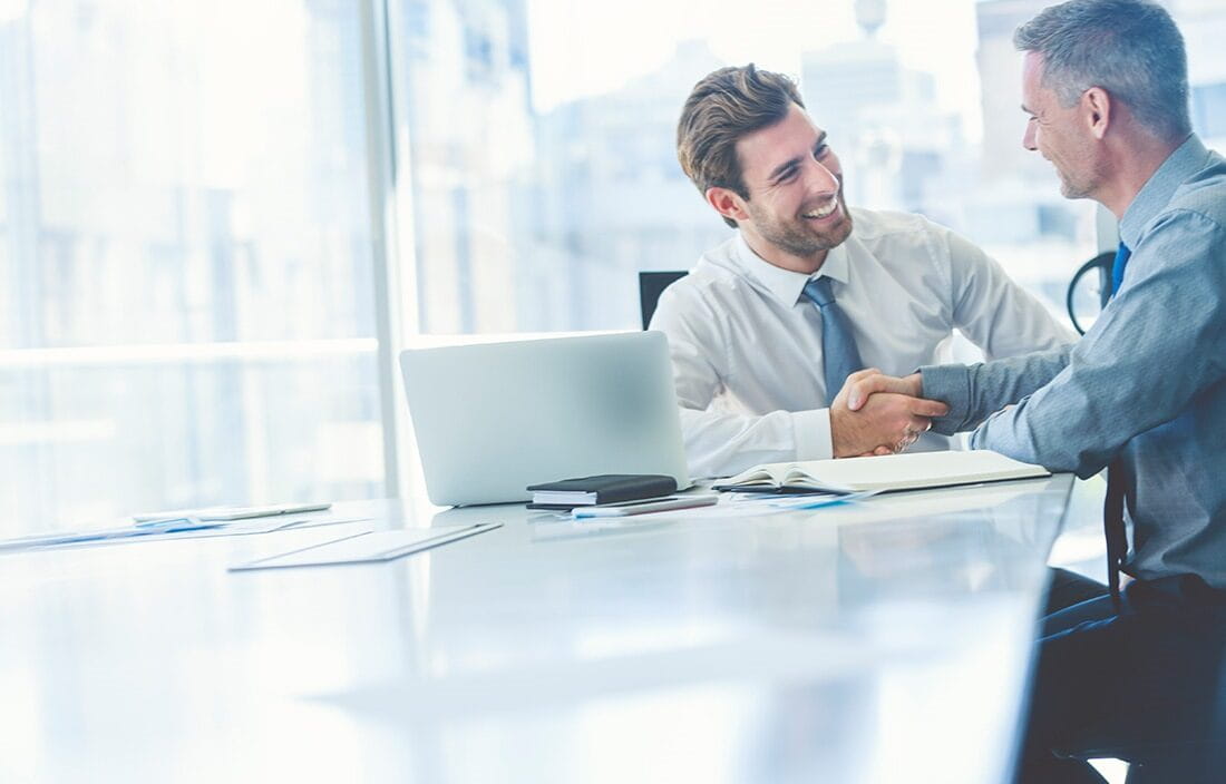 Business professionals talking and shaking hands in an office conference room