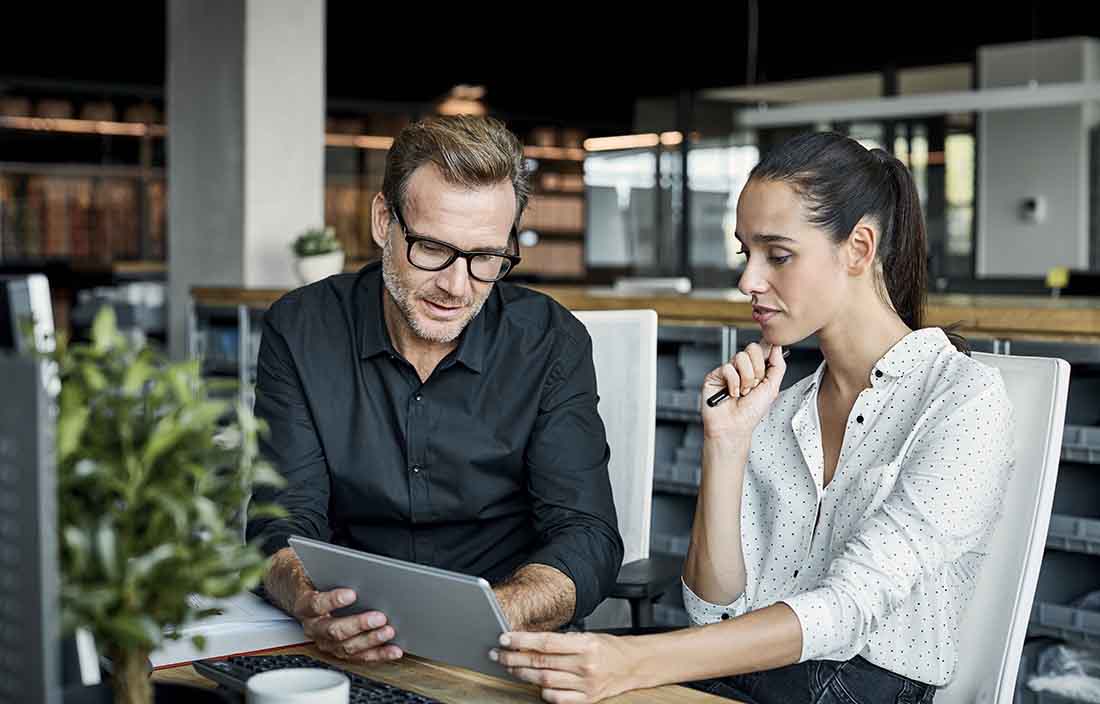 Two business professionals reviewing information together on a tablet device.