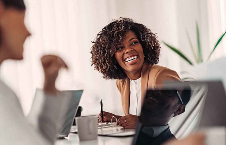 Business professional laughing and smiling while taking notes.