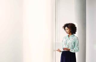 Business professional holding a laptop while standing.