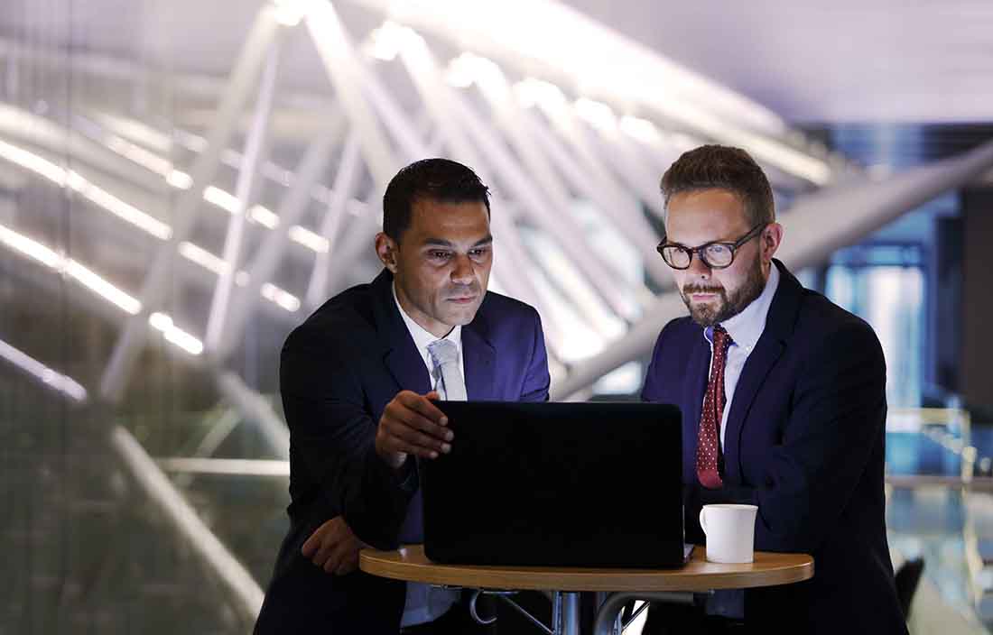 Two business professionals looking at a laptop computer screen.