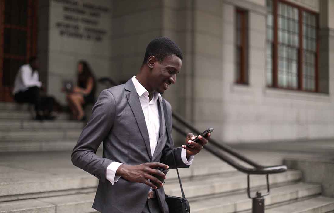 Business professional waling down concrete steps while checking their cell phone.