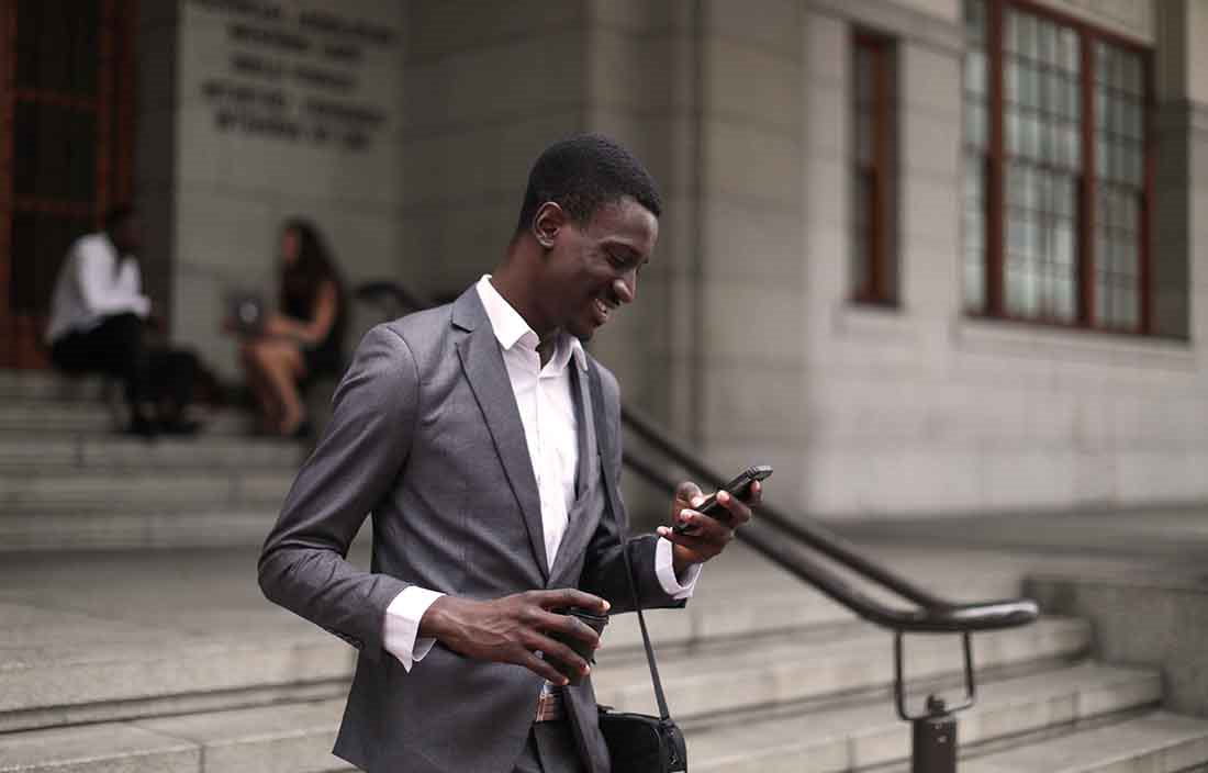 Business professional walking outside a courthouse checking their cell phone.