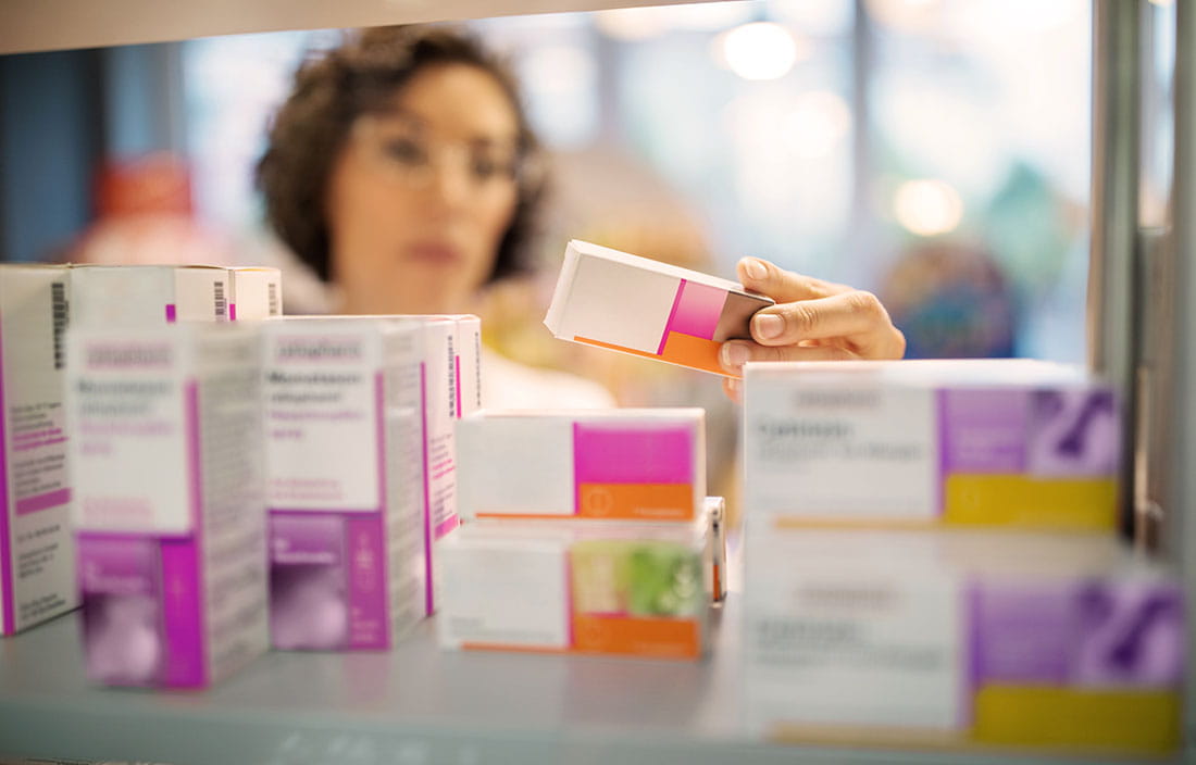 Pharmacy technician examining a box of medicine.