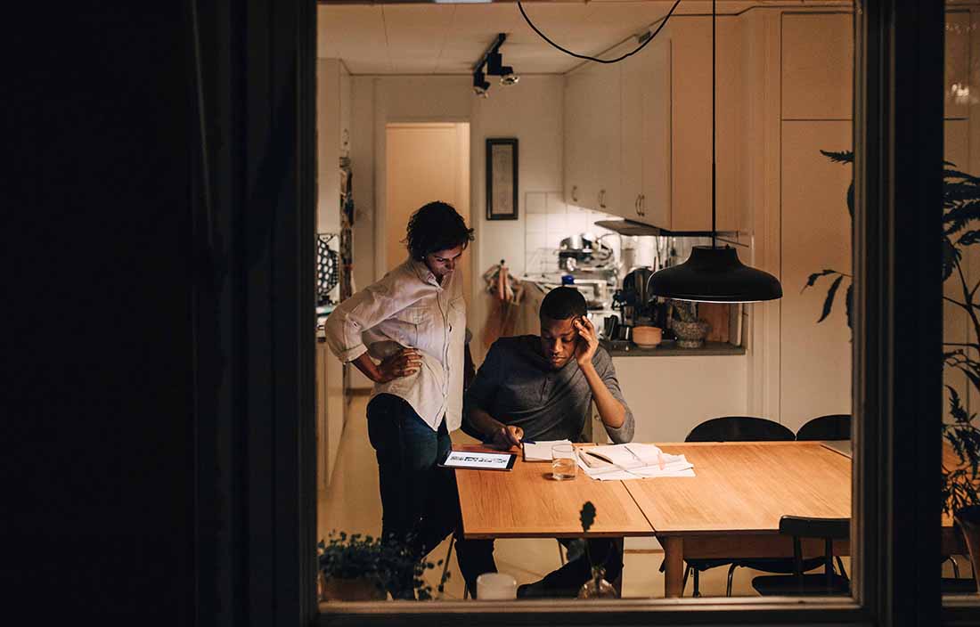 Couple sitting at a kitchen table reviewing information on a notepad.