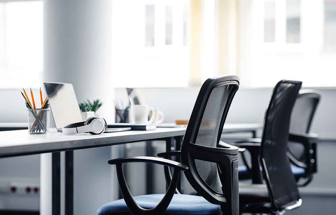 View of an office chair next to an empty desk.