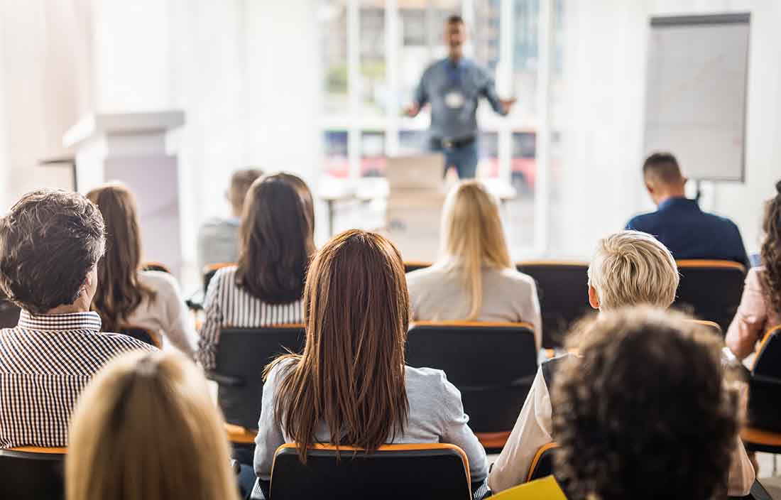 Members of an audience at a conference listening to a speaker.