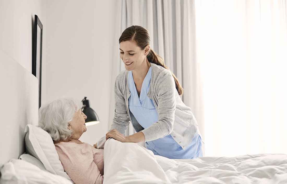 A nurse assisting an elderly patient in bed.