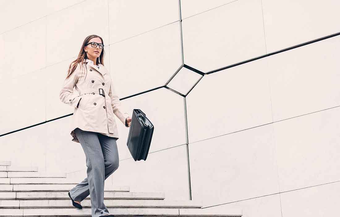Business professional walking down a flight of stairs holding a briefcase.
