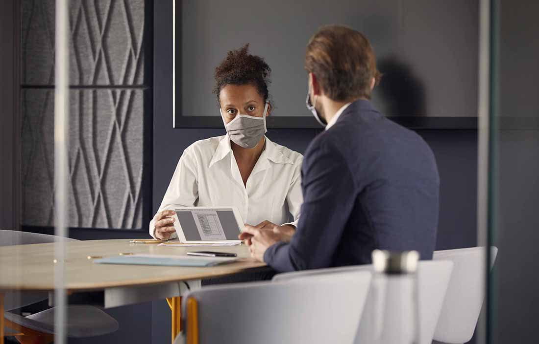 Business professionals meeting while wearing protective facemasks.