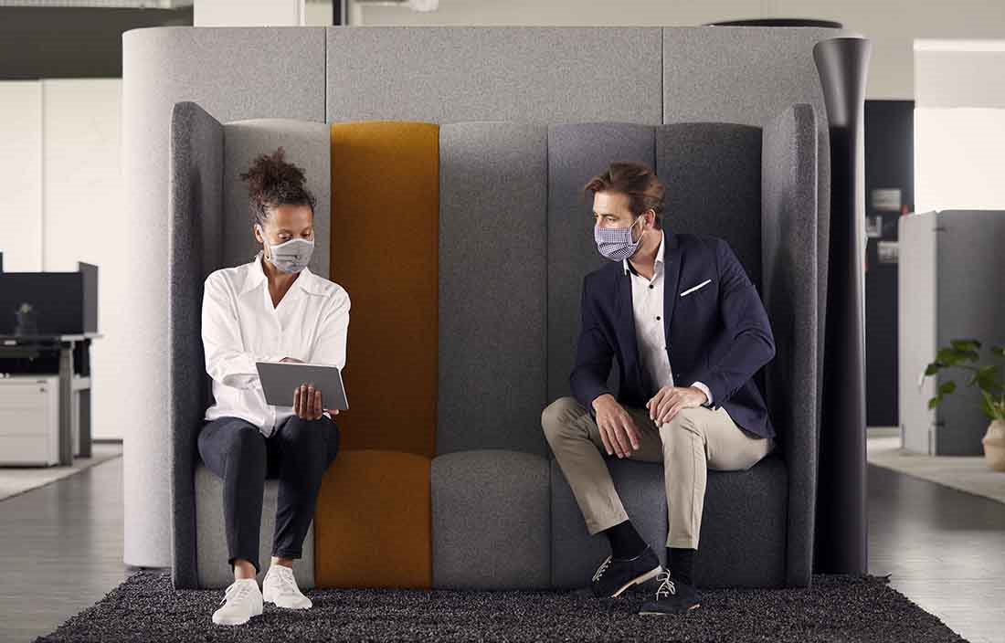 Two business professionals wearing protective facemasks in an office setting.