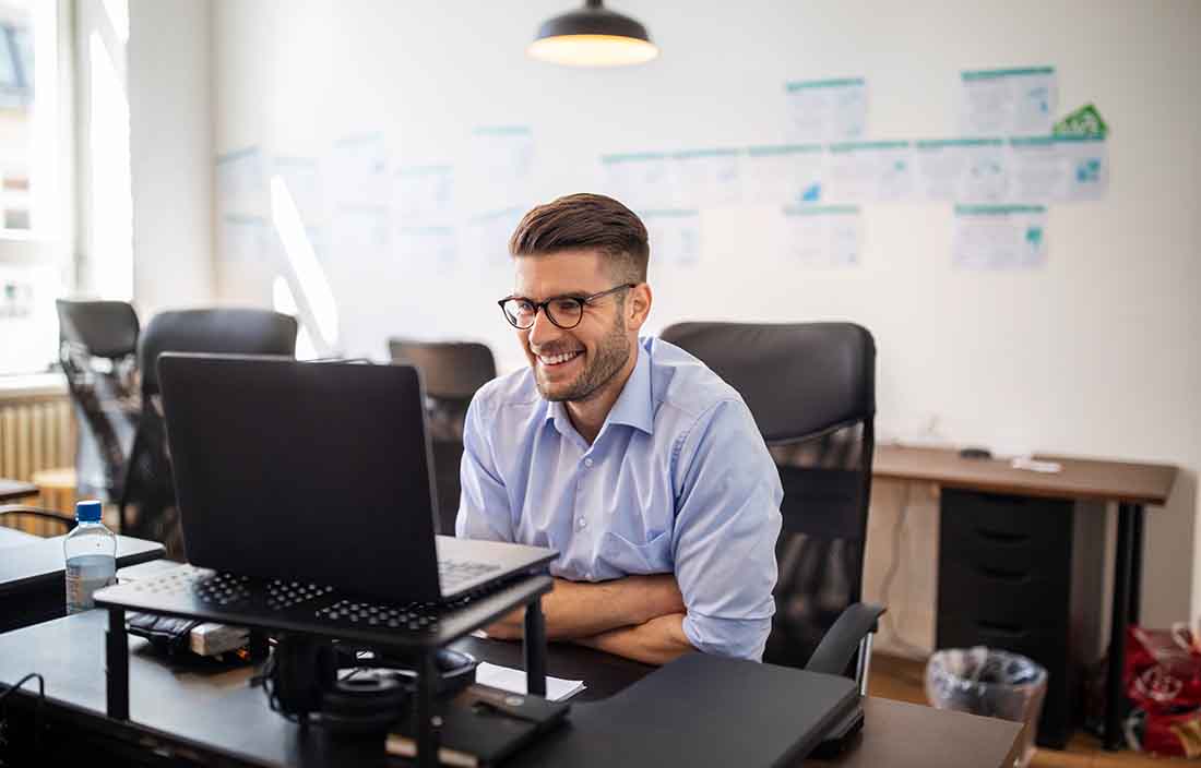 Business professional smiling while using their desktop computer.