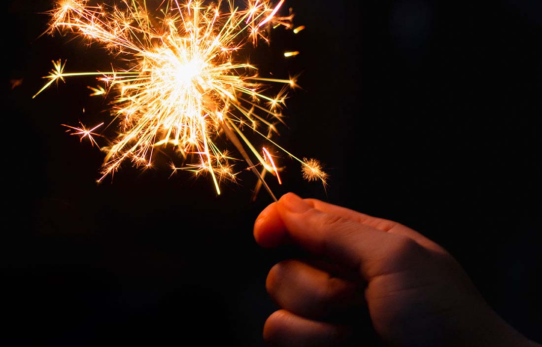 Close-up view of a hand holding a sparkler firework.