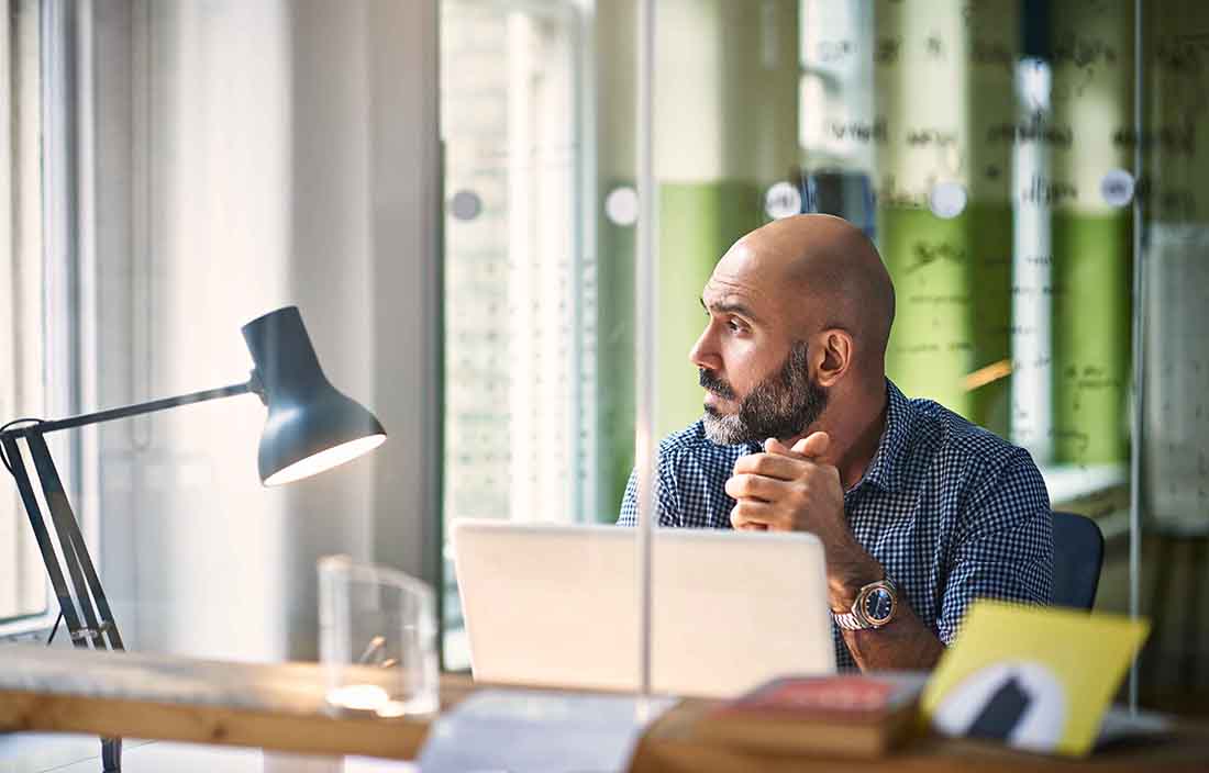 Business professional sitting at a desk looking out the window.