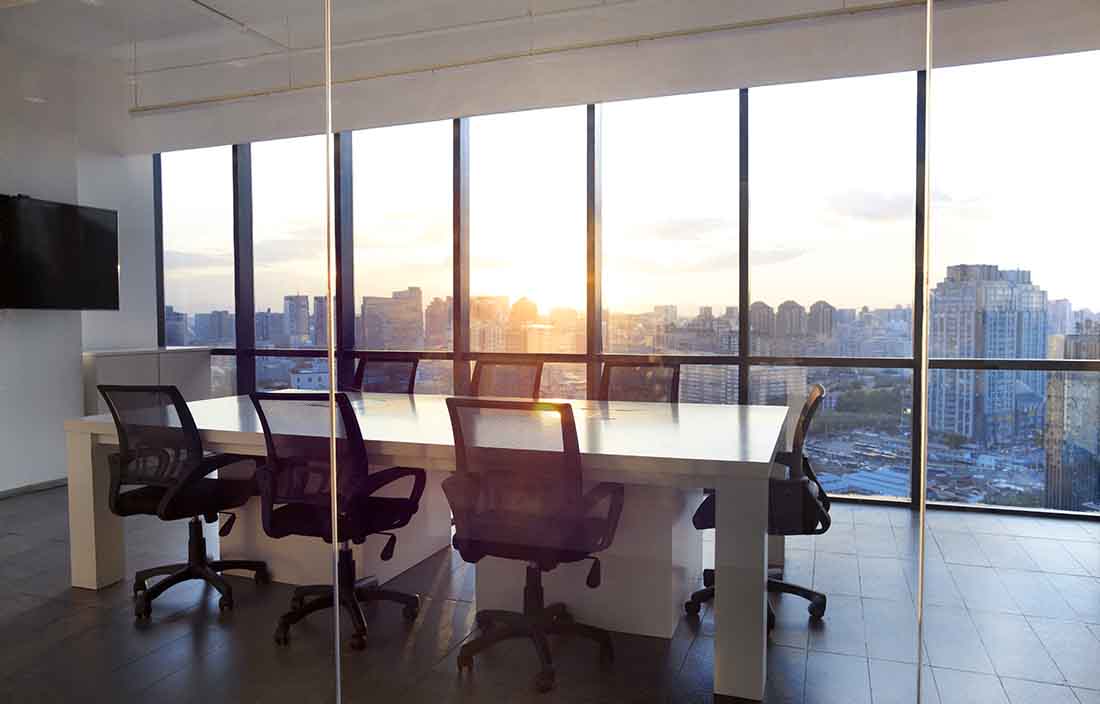 Empty conference room with a view of the sun rising through the glass windows.